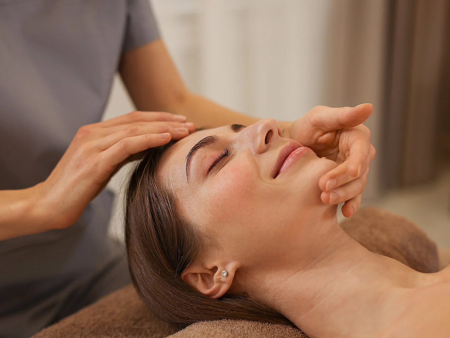 Beautiful woman receiving facial massage indoors, closeup